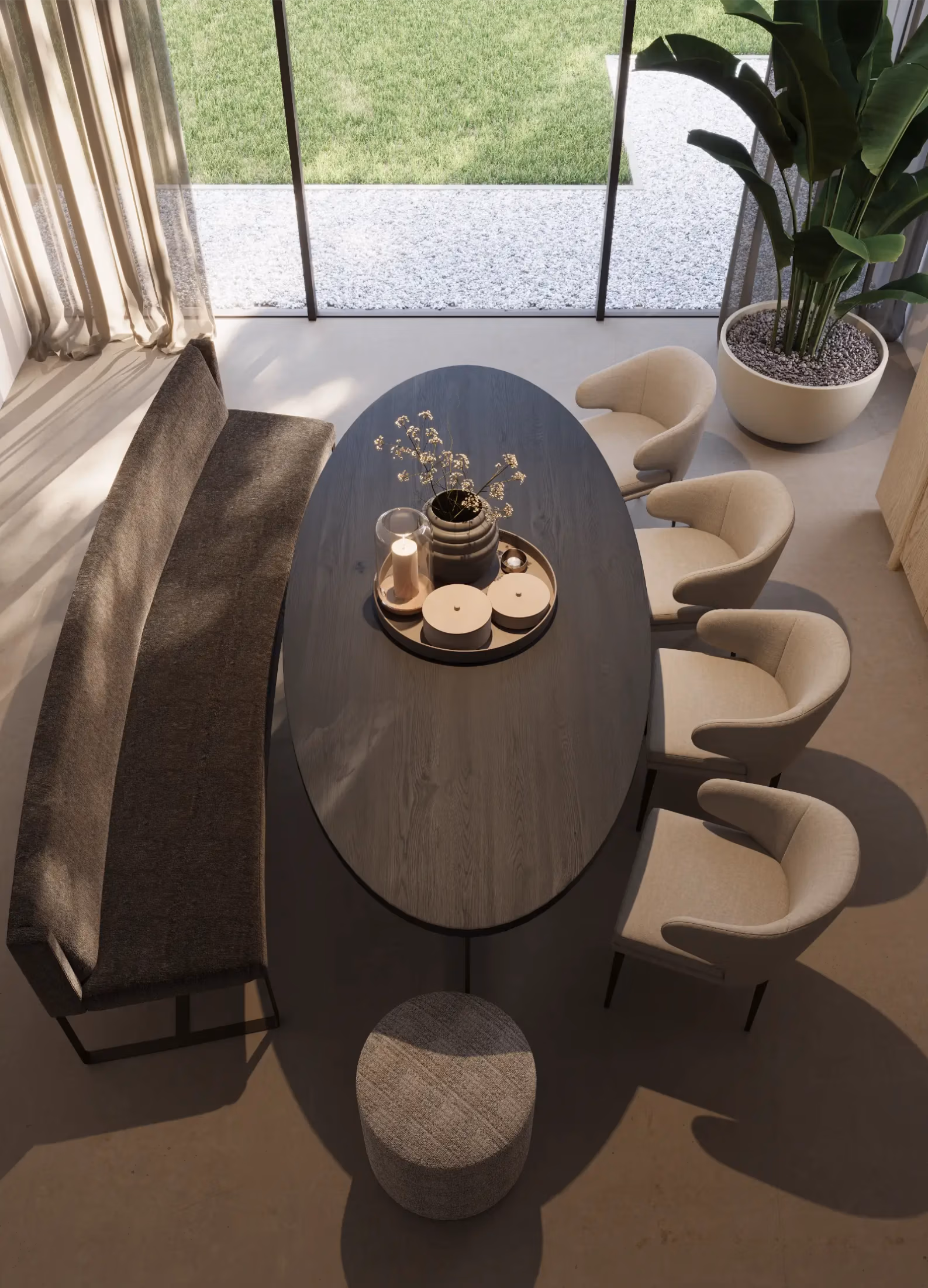 Moderne eethoek met een ovale donkere tafel, vijf beige stoelen, een donkere gebogen bank, een ronde grijze kruk, een grote potplant en zonlicht dat door ramen van vloer tot plafond naar het gras schijnt.