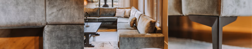 Moderne woonkamer met een grote, L-vormige grijze bank, een houten salontafel en grote ramen die veel natuurlijk licht binnenlaten. Als je op zoek bent naar een bank, zul je de close-up van de bekleding en de poten van de bank op de voorgrond zeker waarderen; deze bieden inspiratie voor zowel stijl als comfort.